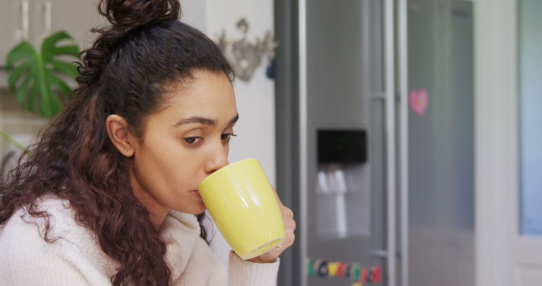 Young woman sipping hot drink in cozy kitchen - Free Images, Stock Photos and Pictures on Pikwizard.com