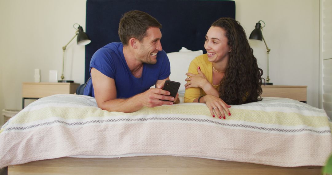 Happy Couple Relaxing on Bed with Smartphone