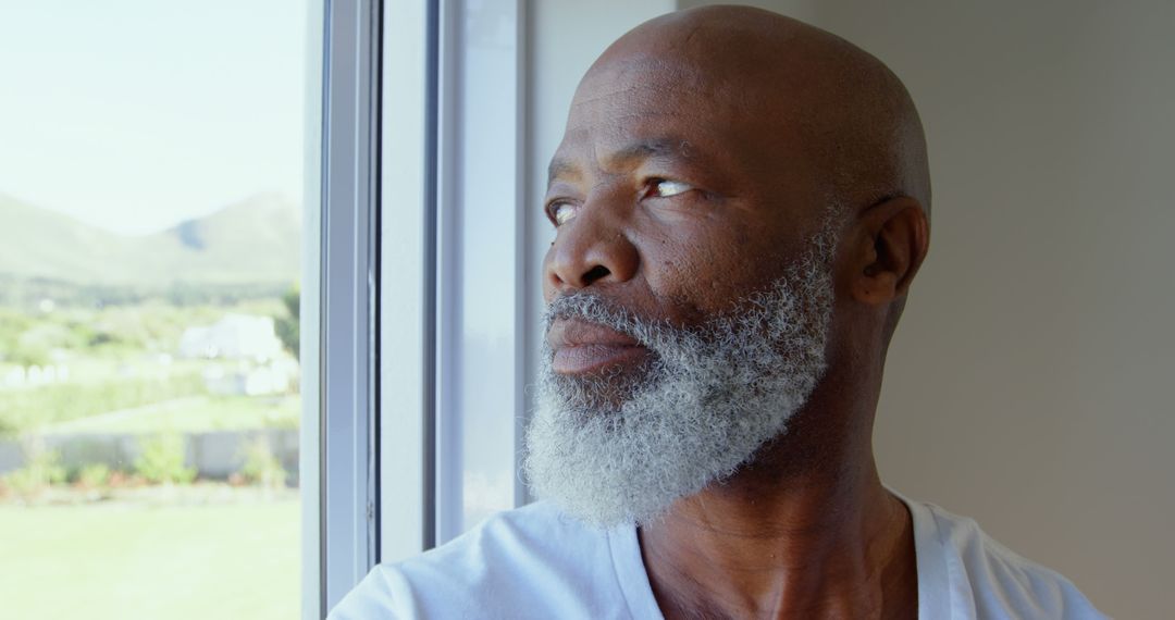 Side view of mature black man looking through window in a comfortable home - Free Images, Stock Photos and Pictures on Pikwizard.com