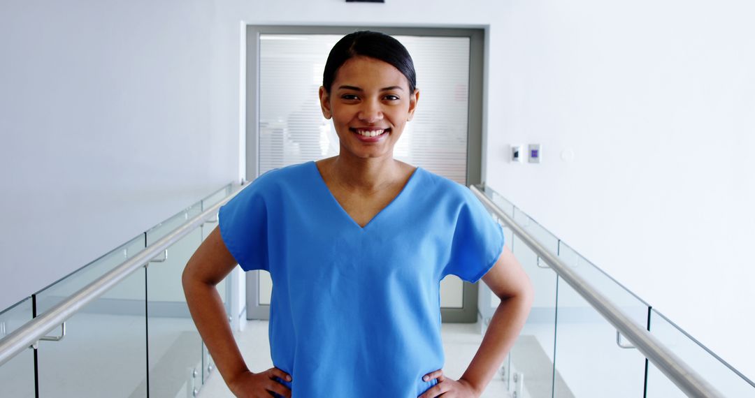 Smiling Female Nurse in Blue Uniform Standing in Hospital Hallway - Free Images, Stock Photos and Pictures on Pikwizard.com