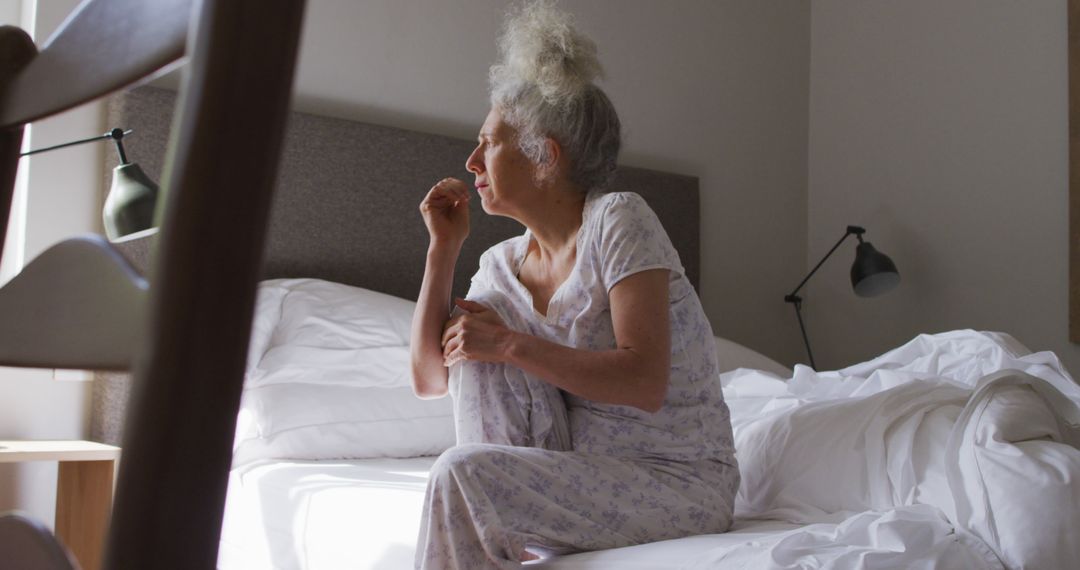 Senior Woman Sitting on Bed in Morning Light at Home - Free Images, Stock Photos and Pictures on Pikwizard.com