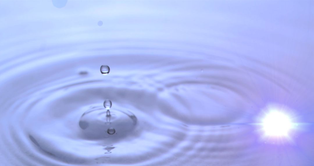 Serene Water Droplet Creating Concentric Ripples with Soft Lens Flare