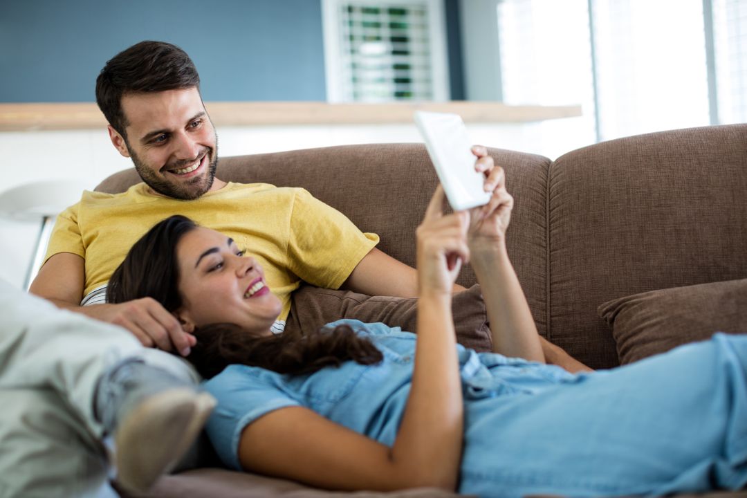 Happy Couple Relaxing on Sofa Using Digital Tablet - Free Images, Stock Photos and Pictures on Pikwizard.com