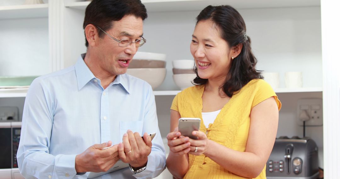 Smiling Couple Using Smartphones in Modern Kitchen - Free Images, Stock Photos and Pictures on Pikwizard.com