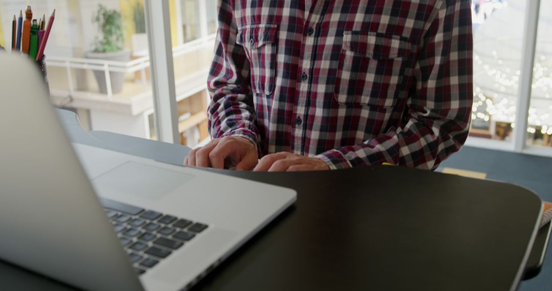 Person Wearing Checkered Shirt Typing on Laptop at Standing Desk - Free Images, Stock Photos and Pictures on Pikwizard.com