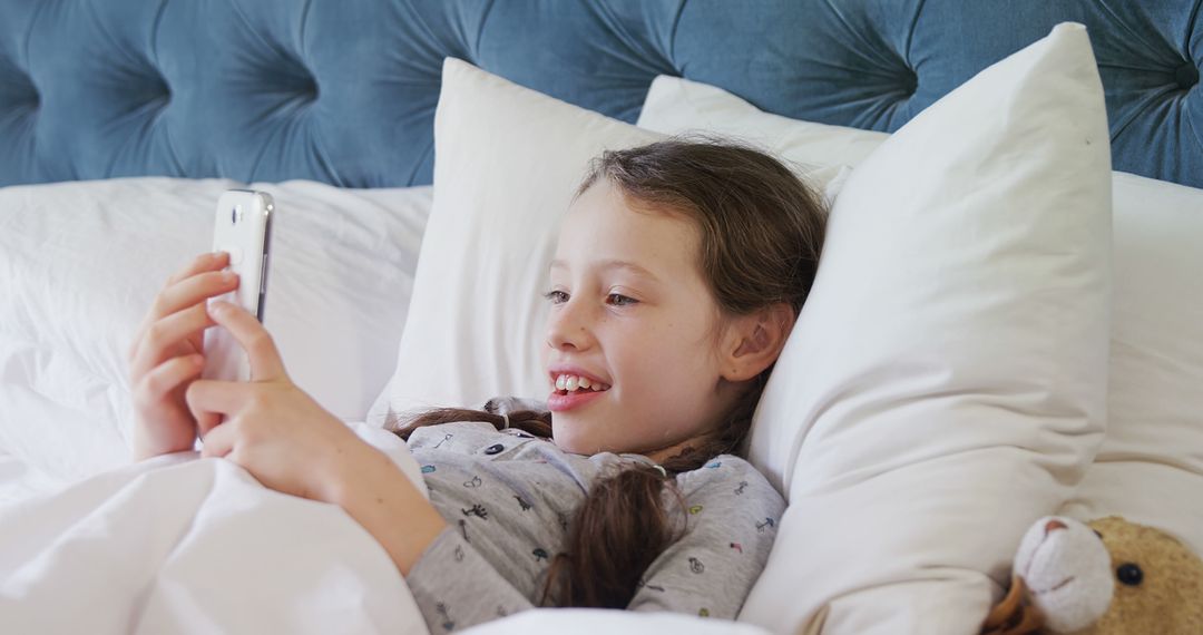 Young Girl Lying in Bed Smiling at Smartphone Screen - Free Images, Stock Photos and Pictures on Pikwizard.com