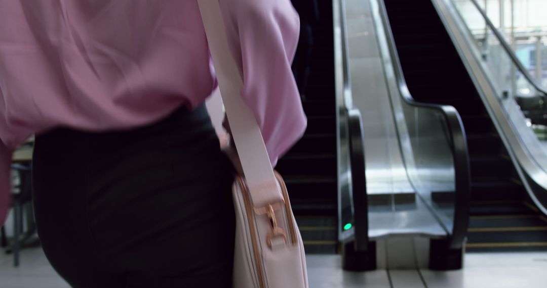 Professional in Pink Shirt Carrying Bag near Escalator - Free Images, Stock Photos and Pictures on Pikwizard.com