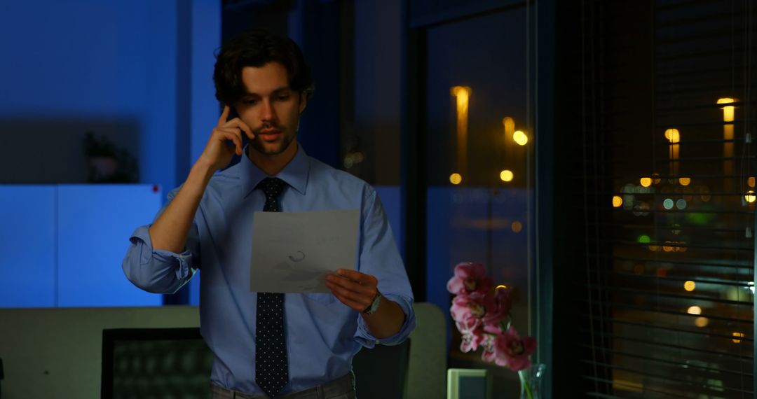 Businessman Working Late on Phone Call Reviewing Documents at Night - Free Images, Stock Photos and Pictures on Pikwizard.com