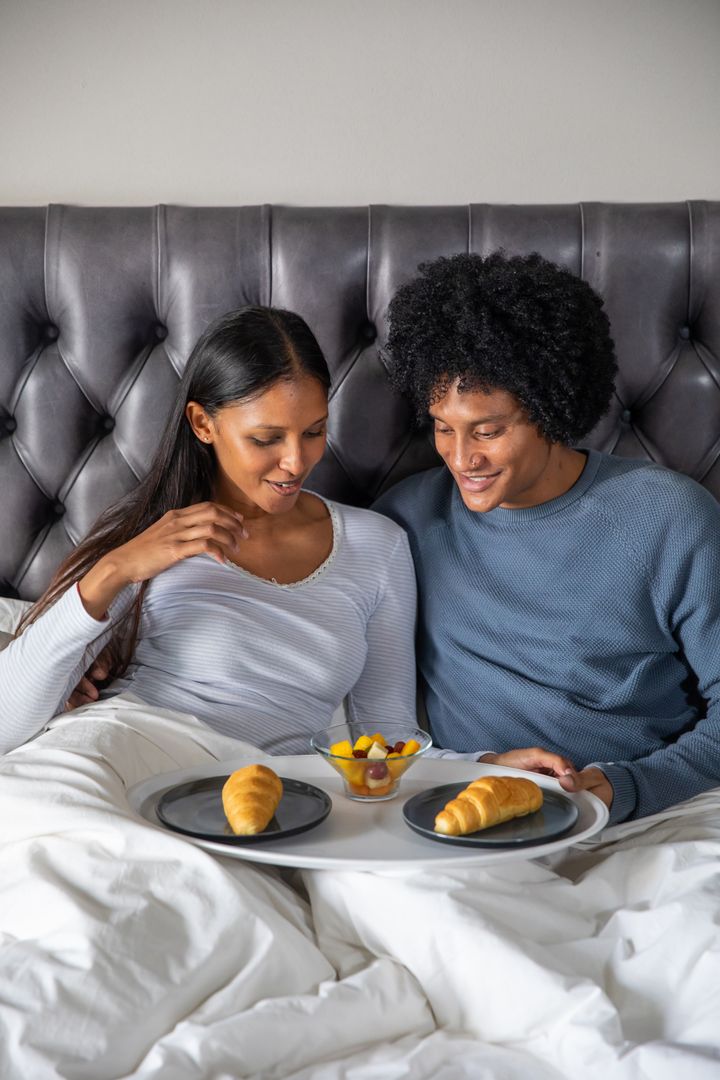 Diverse Couple Enjoying Breakfast in Cozy Bed