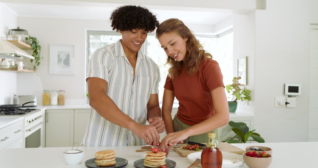 Smiling Multiethnic Couple Preparing Pancakes in Modern Kitchen