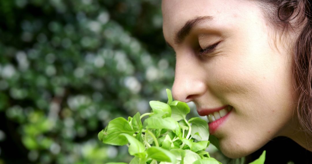 Woman Enjoying Natural Aroma of Fresh Green Plant Outdoors - Free Images, Stock Photos and Pictures on Pikwizard.com