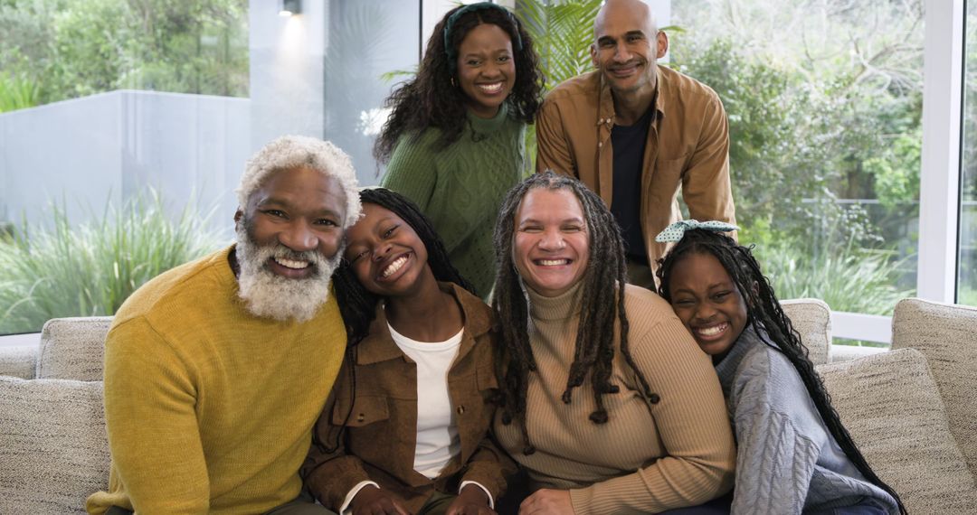 Diverse multigenerational family smiling together on sofa, cozy sunlit home portrait