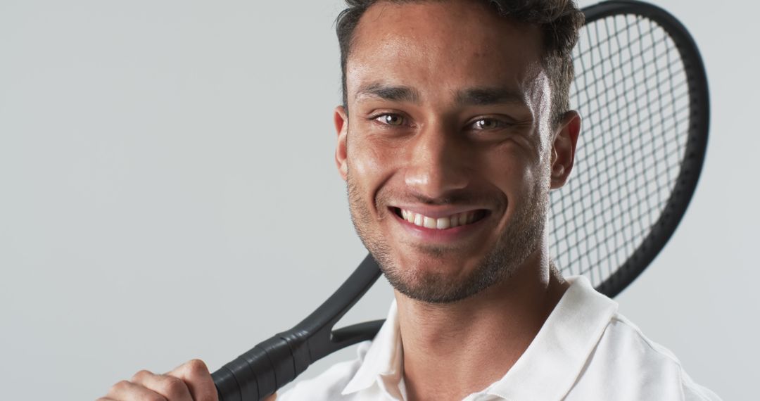 Smiling Biracial Tennis Player Holding Racket in Studio
