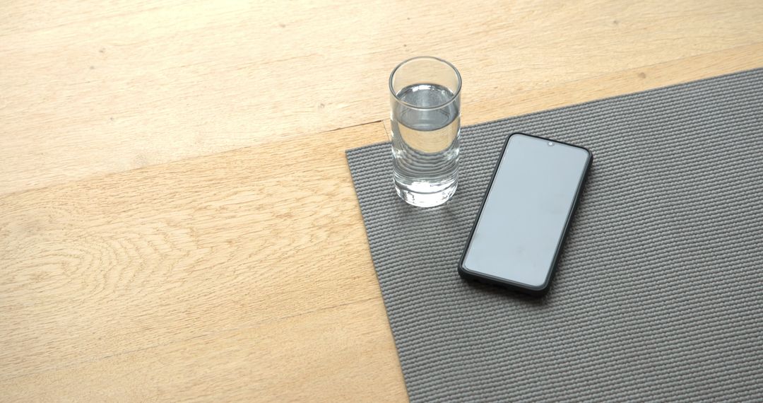 Glass of Water and Smartphone on Gray Exercise Mat