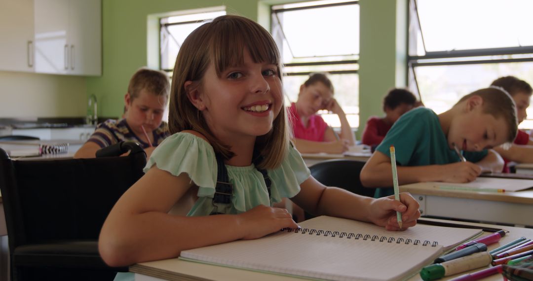 Smiling Girl Completing Schoolwork in Classroom with Classmates - Free Images, Stock Photos and Pictures on Pikwizard.com