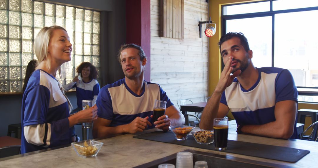 Friends Watching Sports Game in Bar with Drinks and Snacks