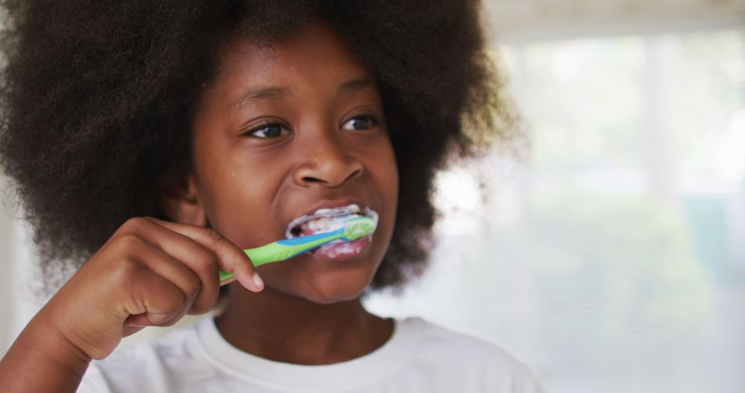 Young African American girl brushing teeth in bathroom - Free Images, Stock Photos and Pictures on Pikwizard.com