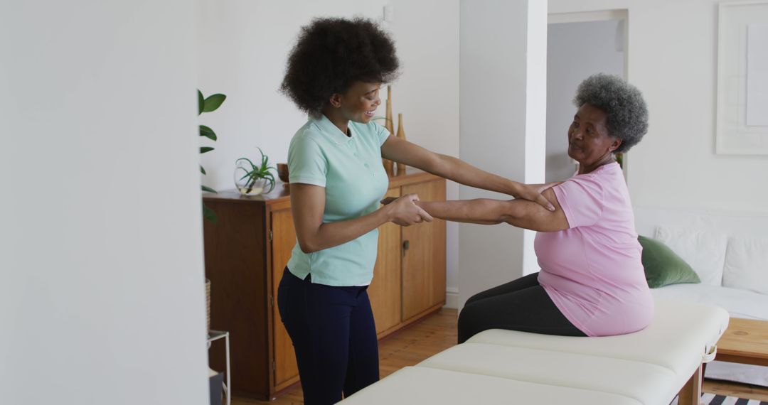 African American Physiotherapist Assisting Senior Woman with Arm Exercises