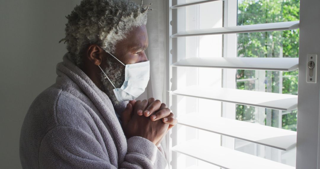 Elderly Man in Mask Standing by Window Reflecting - Free Images, Stock Photos and Pictures on Pikwizard.com