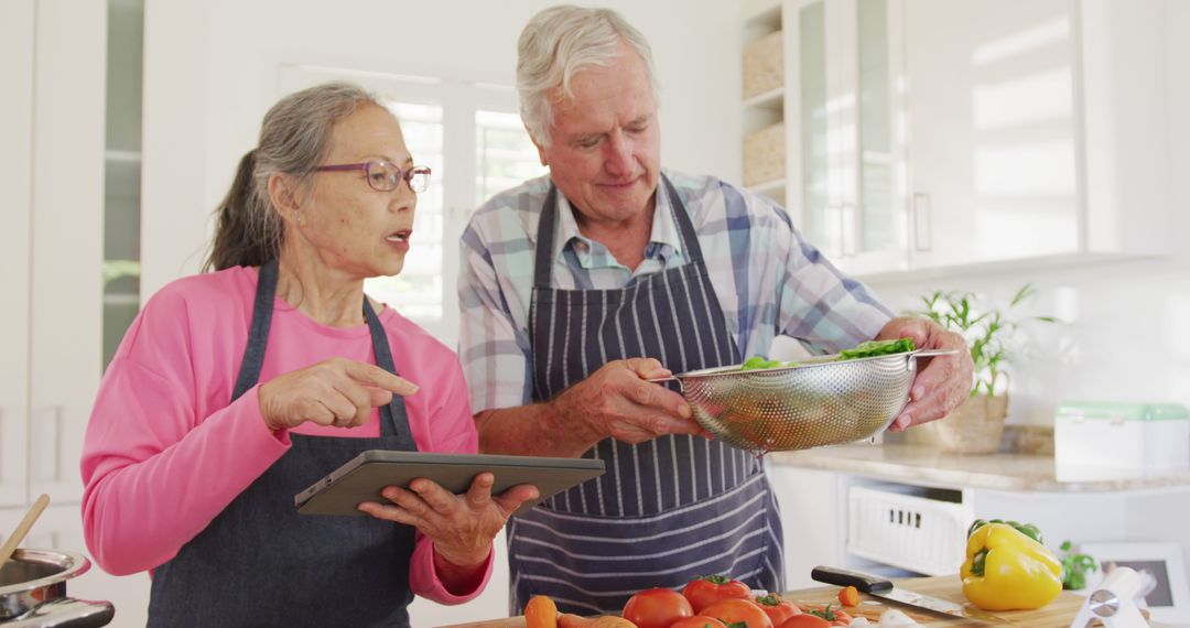 Happy Senior Couple Using Tablet and Cooking Together in Modern Kitchen - Free Images, Stock Photos and Pictures on Pikwizard.com