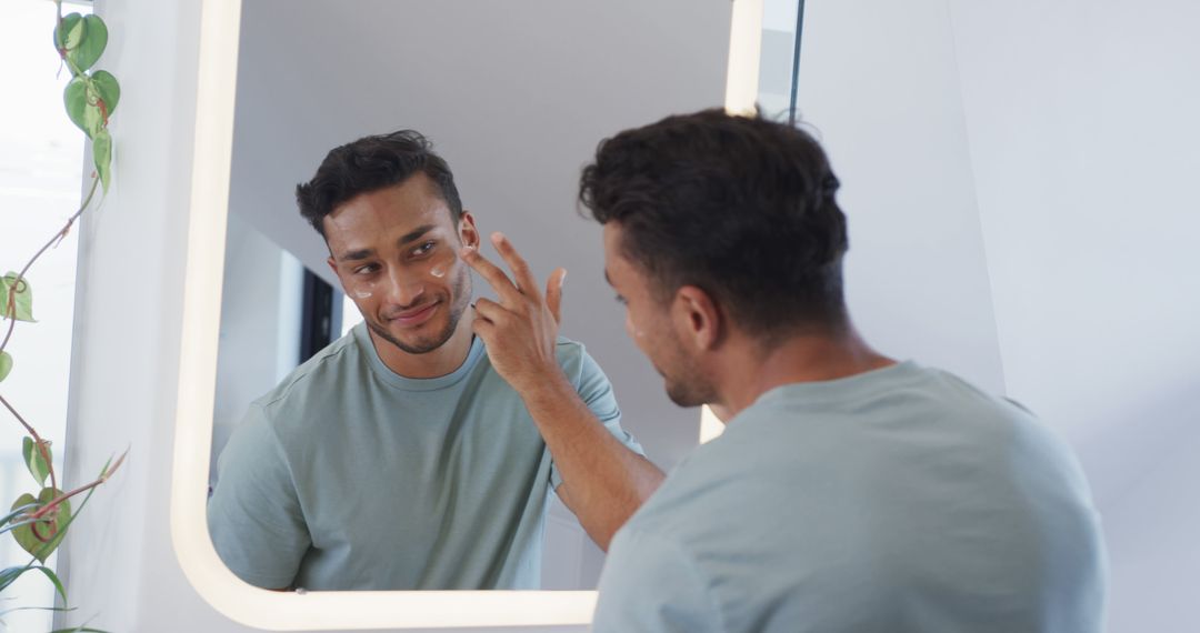 Middle Eastern Man Applying Skincare Cream in Mirror - Free Images, Stock Photos and Pictures on Pikwizard.com