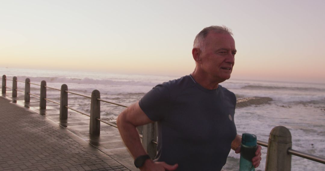 Senior man jogging by the seaside during sunrise - Free Images, Stock Photos and Pictures on Pikwizard.com