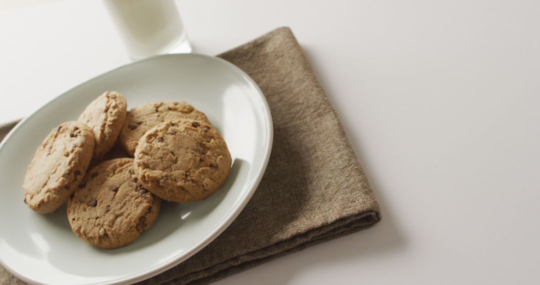 Plate of Chocolate Chip Cookies with Glass of Milk on Brown Napkin - Free Images, Stock Photos and Pictures on Pikwizard.com