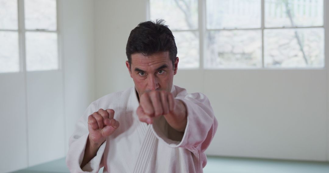 Focused Man Practicing Martial Arts Punch in Bright Room - Free Images, Stock Photos and Pictures on Pikwizard.com