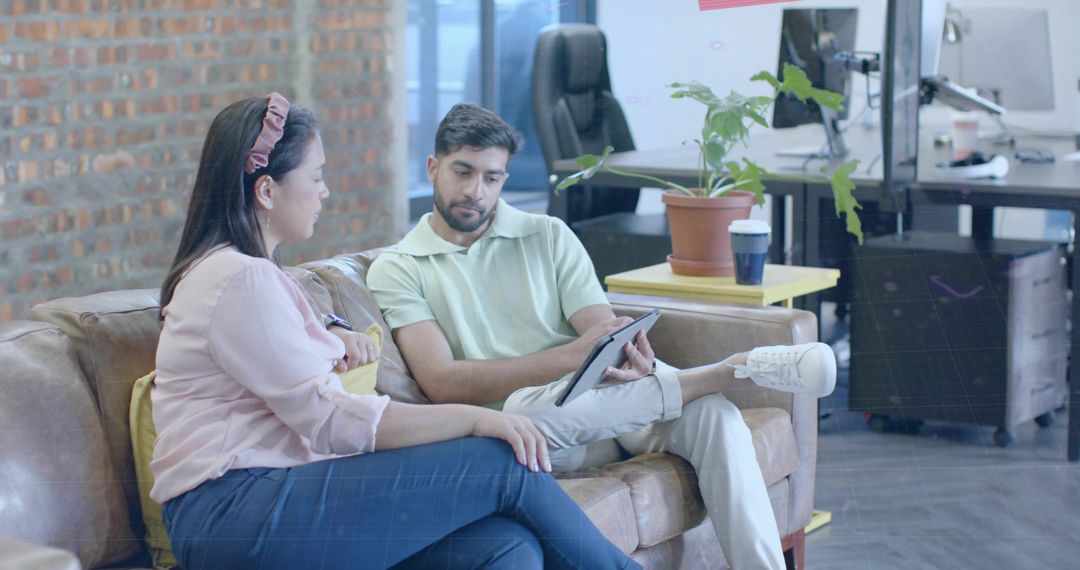 Coworkers Discussing Tablet Content in Modern Office Lounge