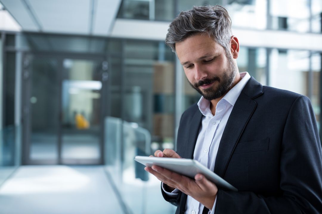 Businessman Using Tablet for Professional Task in Modern Office Corridor