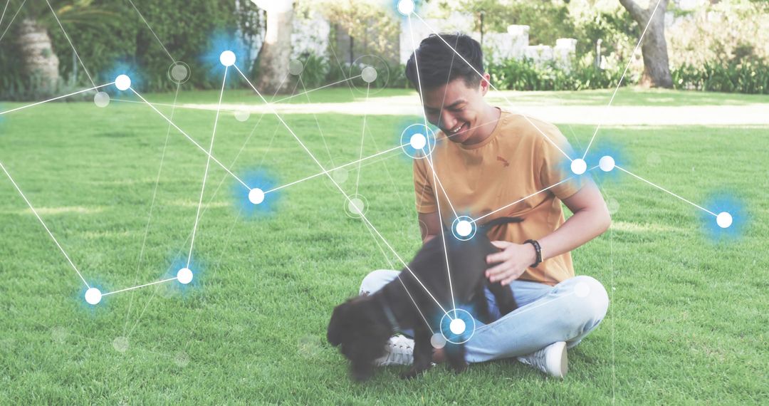 Asian man sitting on grass petting puppy wearing fitness tracker with network overlay