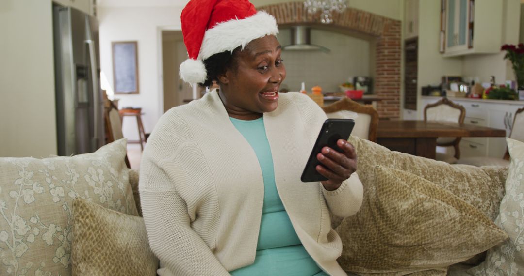 Excited Woman in Santa Hat Video Calling at Home During Christmas - Free Images, Stock Photos and Pictures on Pikwizard.com