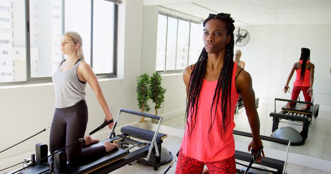 Two Women Exercising on Pilates Machines in Bright Fitness Studio - Free Images, Stock Photos and Pictures on Pikwizard.com