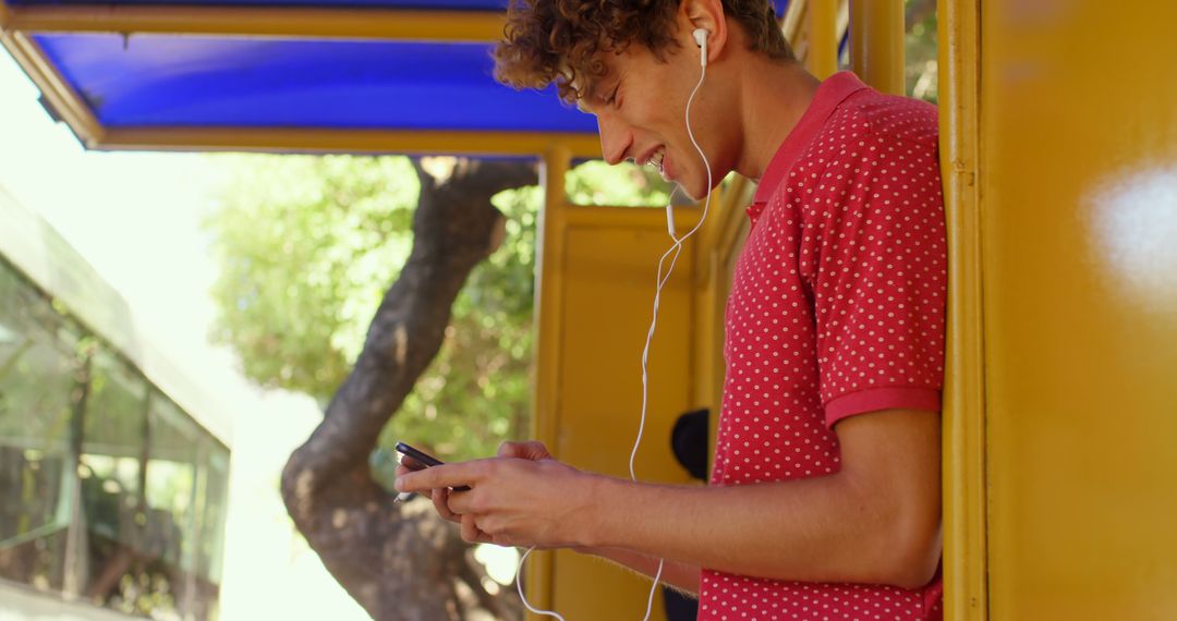 Smiling Young Man Using Smartphone at Bus Stop - Free Images, Stock Photos and Pictures on Pikwizard.com