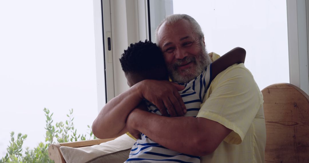 Senior biracial man embraces an African American boy at home - Free Images, Stock Photos and Pictures on Pikwizard.com
