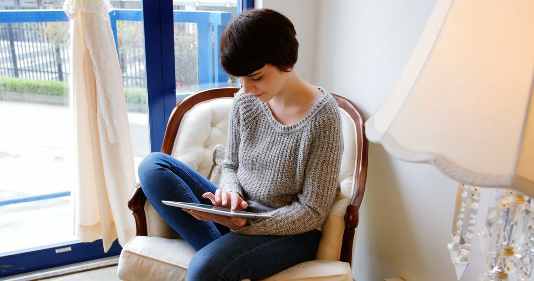 Young Woman Using Tablet by Window on a Rainy Day - Free Images, Stock Photos and Pictures on Pikwizard.com