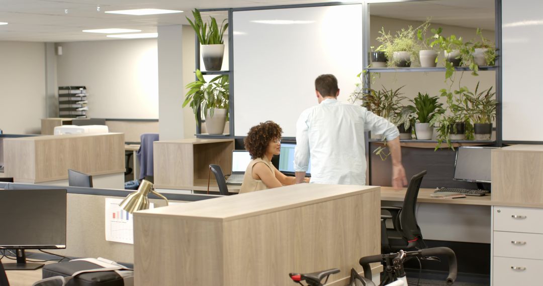 Coworkers Collaborating at Open Office Desk with Greenery and Bicycle