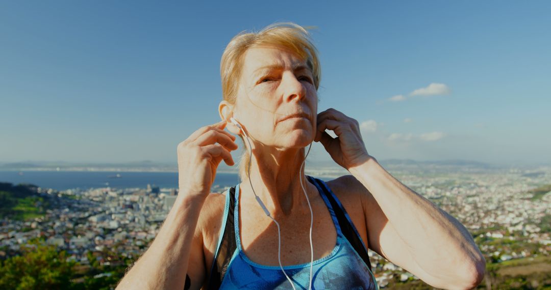 Senior Woman Adjusting Earbuds During Outdoor Exercise Routine - Free Images, Stock Photos and Pictures on Pikwizard.com