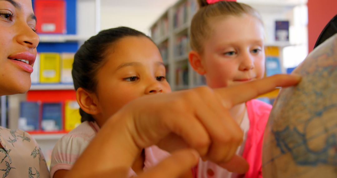 Engaged Teacher With Kids Exploring Globe in Library