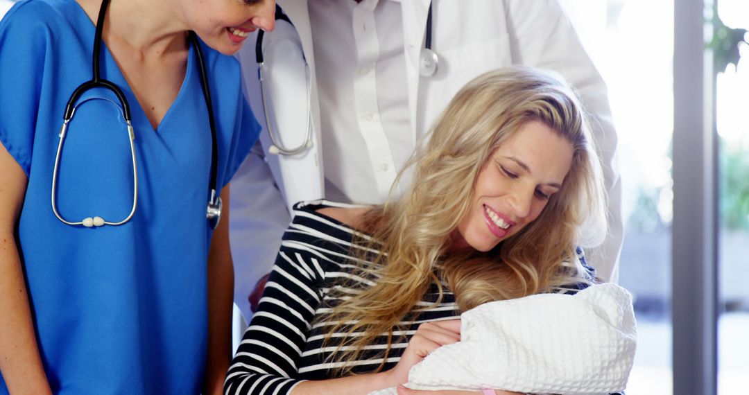 Young Mother Holding Newborn Surrounded By Healthcare Workers - Free Images, Stock Photos and Pictures on Pikwizard.com