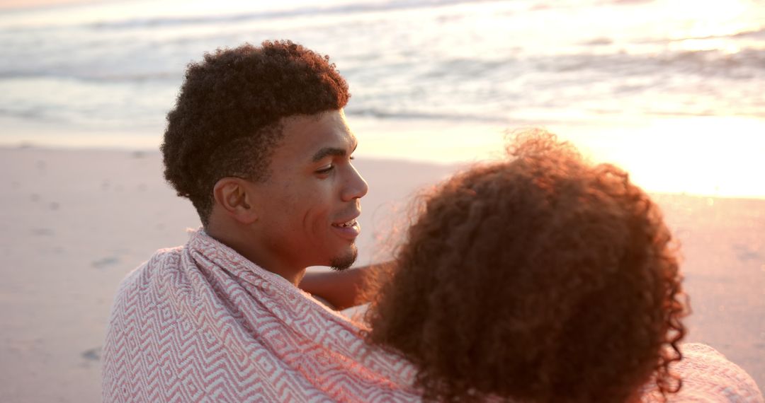 Couple Embracing on Beach During Sunset Wrapped in Blanket