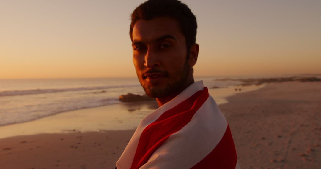 Man Draped in Blanket Standing on Beach at Sunset - Free Images, Stock Photos and Pictures on Pikwizard.com