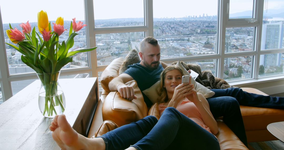 Couple Relaxing in Modern Apartment with City View - Free Images, Stock Photos and Pictures on Pikwizard.com