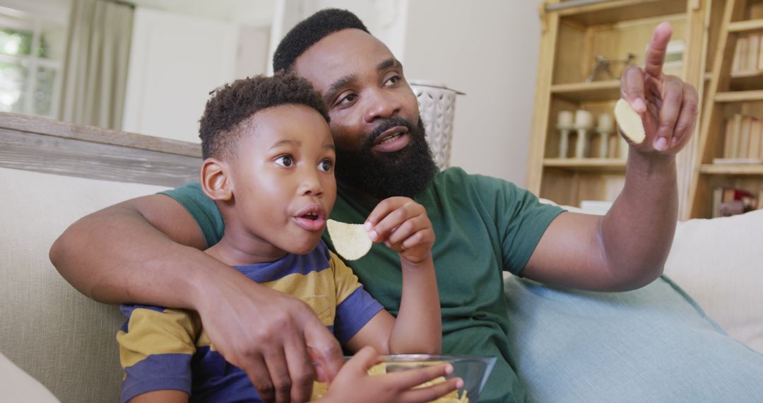 Father and Son Enjoying Snack Watching TV Together - Free Images, Stock Photos and Pictures on Pikwizard.com