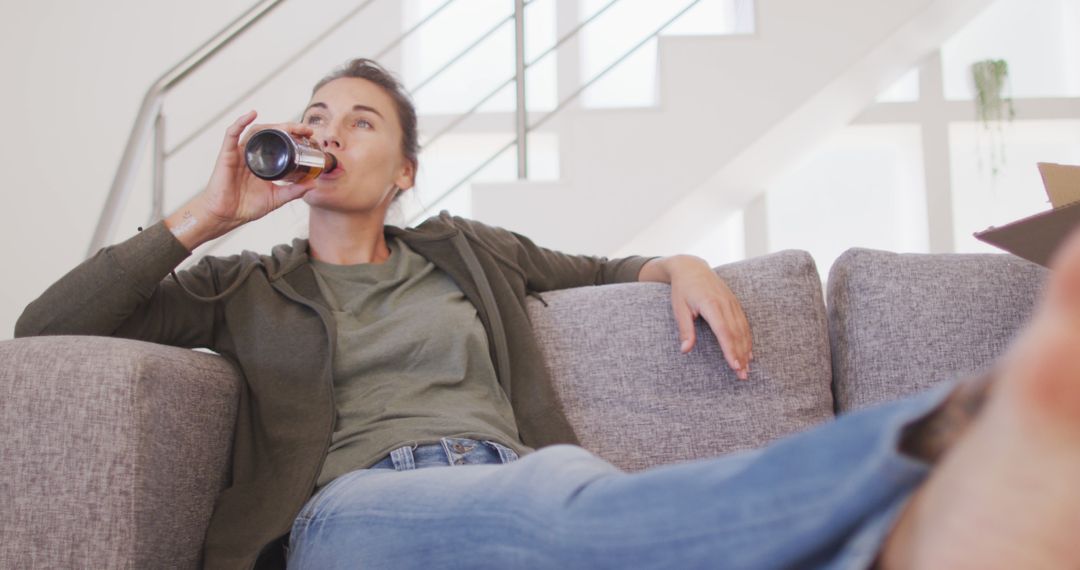 Relaxed Woman Drinking Beer While Lounging on Sofa at Home - Free Images, Stock Photos and Pictures on Pikwizard.com