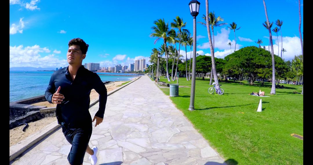 Man jogging along tropical beachfront pathway on sunny day - Free Images, Stock Photos and Pictures on Pikwizard.com