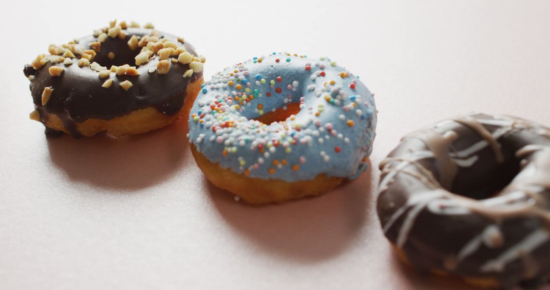 Assorted Glazed Donuts with Colorful Sprinkles and Nuts on Light Background - Free Images, Stock Photos and Pictures on Pikwizard.com