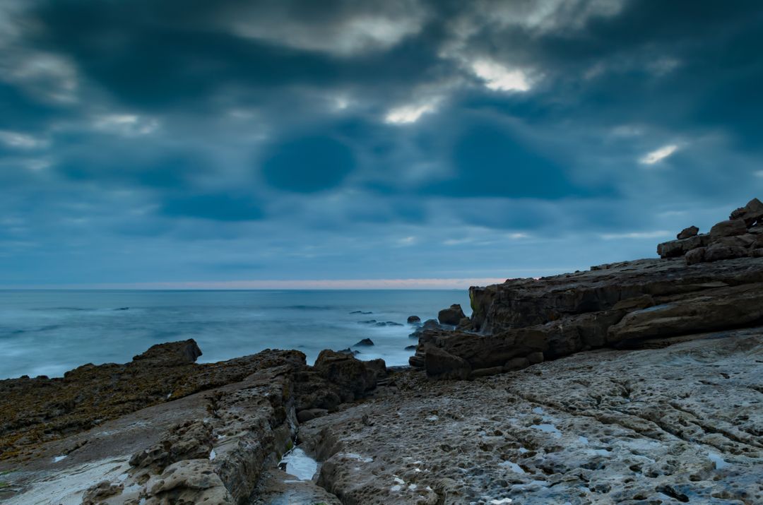 Dramatic Seaside Cliff under Dark Cloudy Sky at Dusk - Free Images, Stock Photos and Pictures on Pikwizard.com