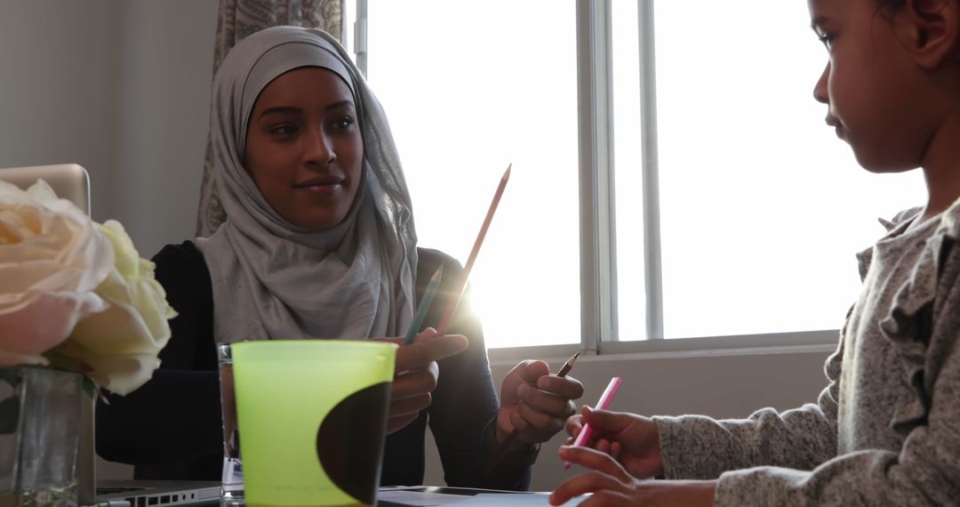 Young Mother in Hijab Coloring with Daughter at Home