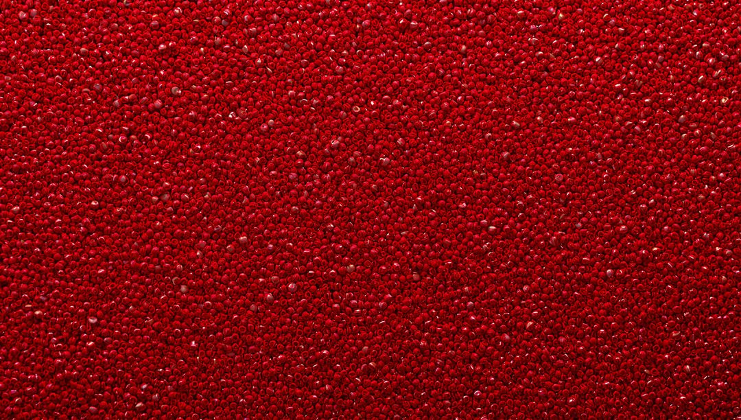 Macro glossy red bead texture shimmering with specular highlights for abstract backgrounds